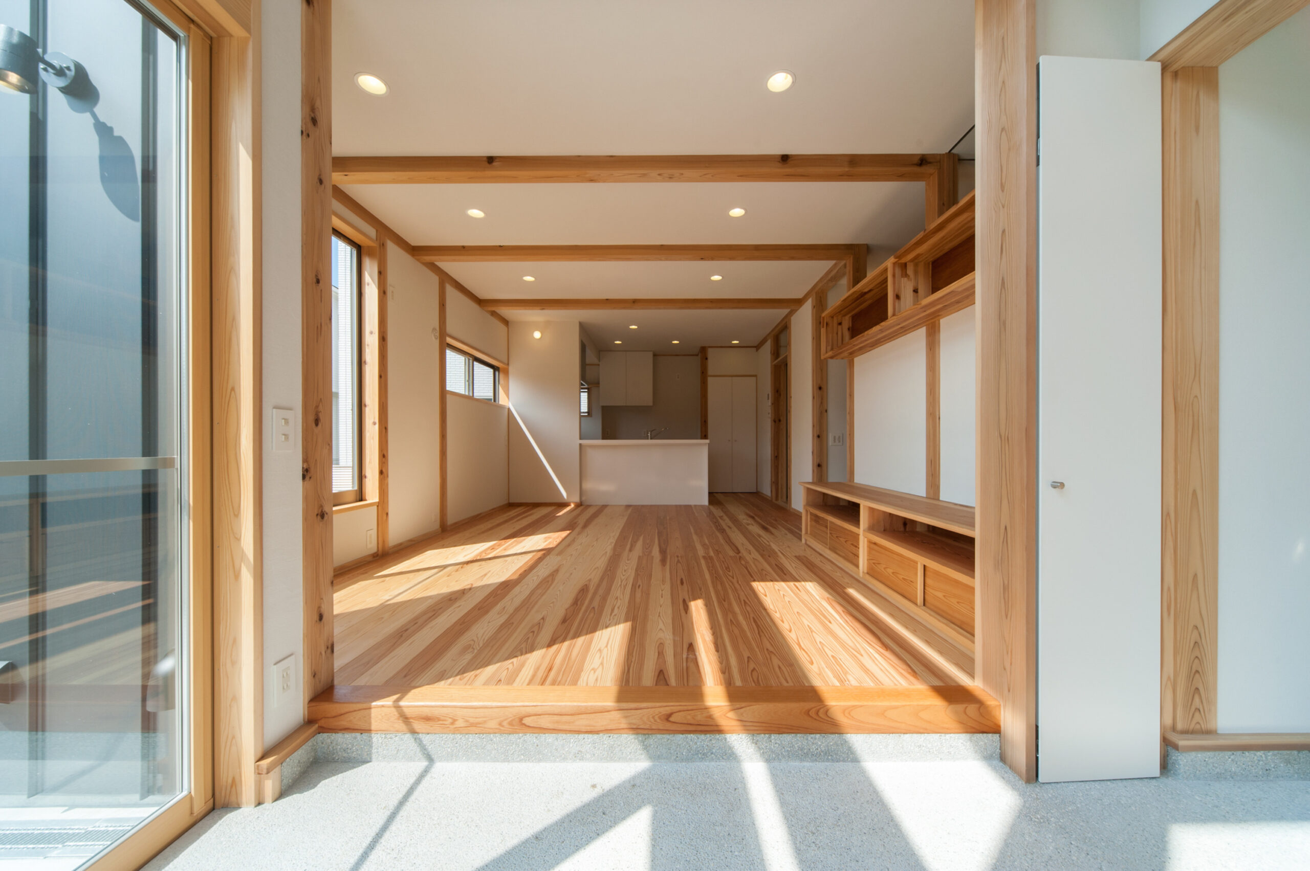玄関の土間から一続きになった、無垢の杉床と造作棚のLDK
