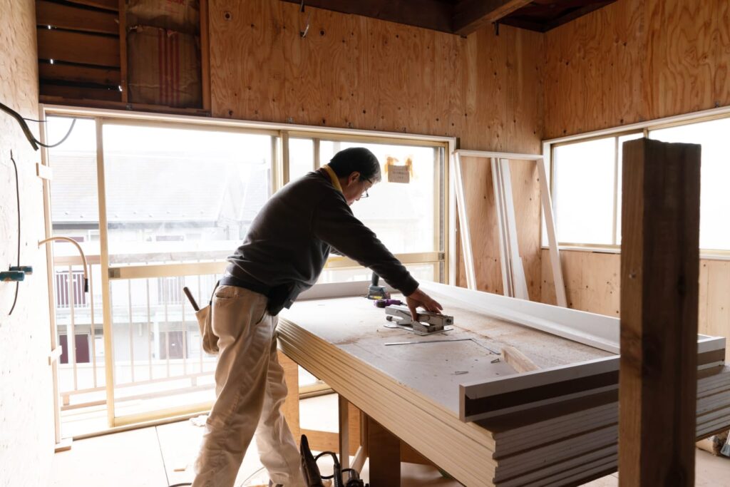木の下地に囲まれた改修現場で、造作材を加工する職人