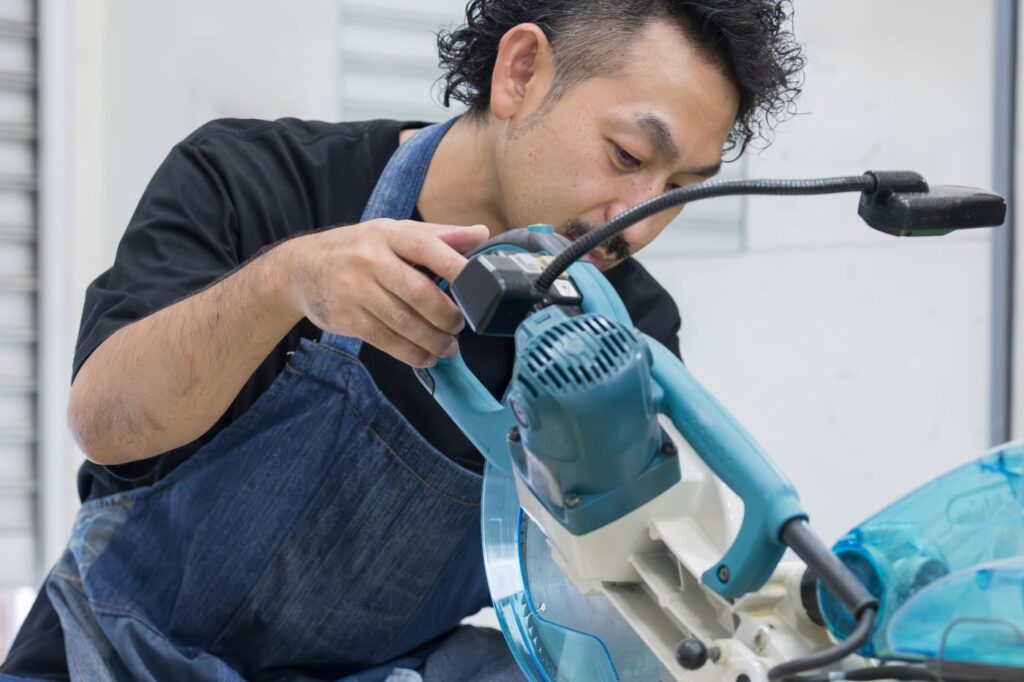 工房で電動工具を使い、木を刻む職人の手元