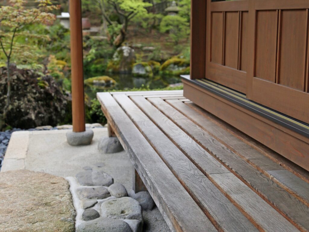 木の濡れ縁と束石、その先に広がる庭の緑と池