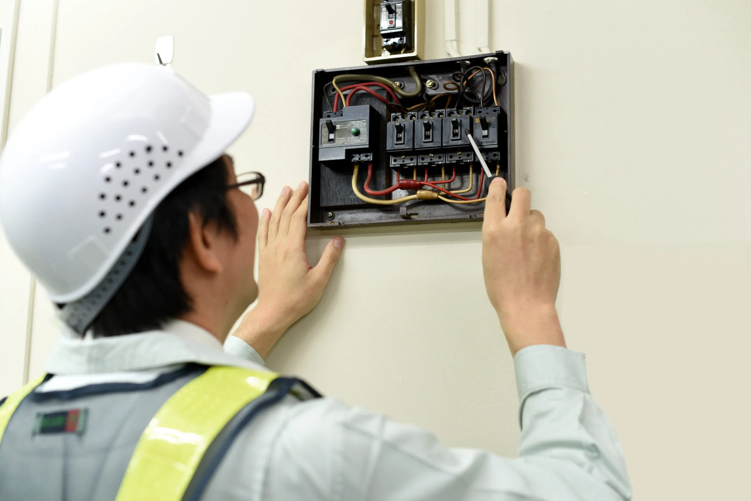 住まいの分電盤を点検する作業員